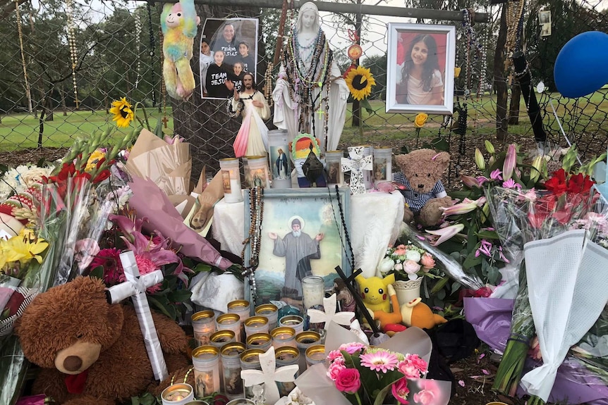 Candles, flowers and photos alongside a footpath