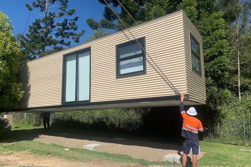 a crane puts the shipping container home in place
