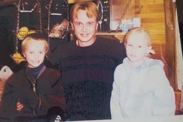 Adrian Trett standing between his children, with his arms around them