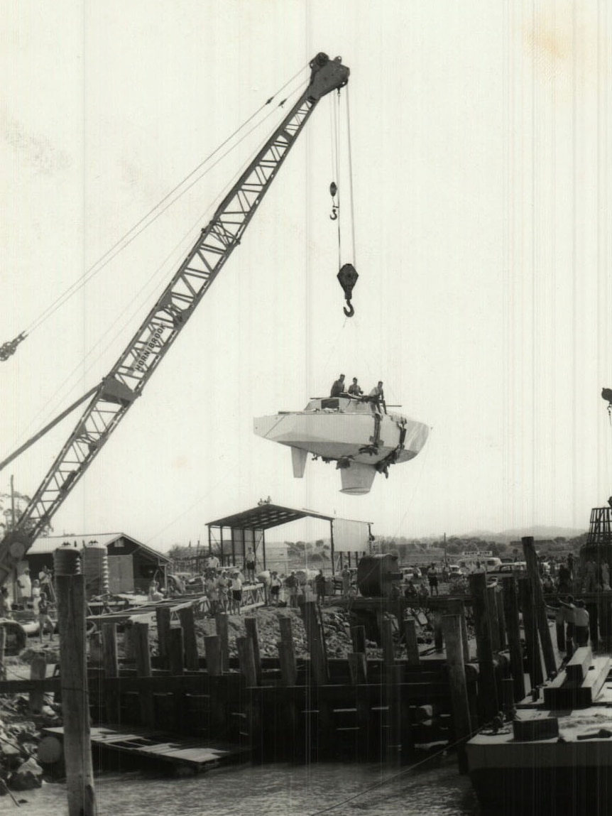 Historic photo of yacht Wistari being lifted by a crane as it is launched in Gladstone harbour in 1965.