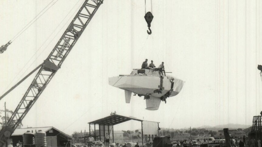Historic photo of yacht Wistari being lifted by a crane as it is launched in Gladstone harbour in 1965.