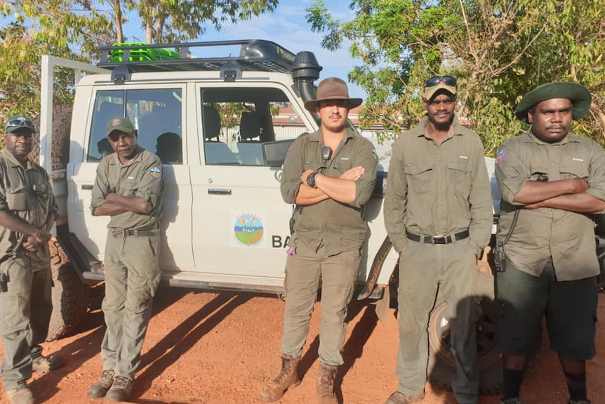 Five Bawinanga Rangers in green uniform stand in front of a white ranger vehicle.