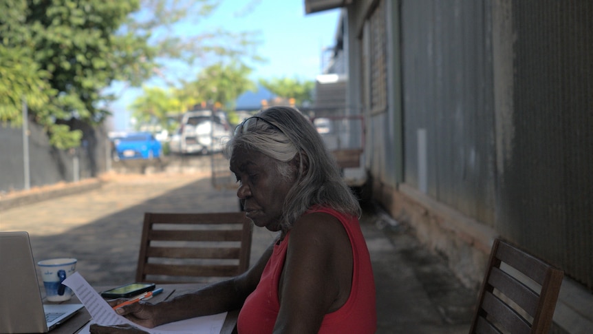 Aboriginal woman Joy Bulkanhawuy sits at a an outdoor setting