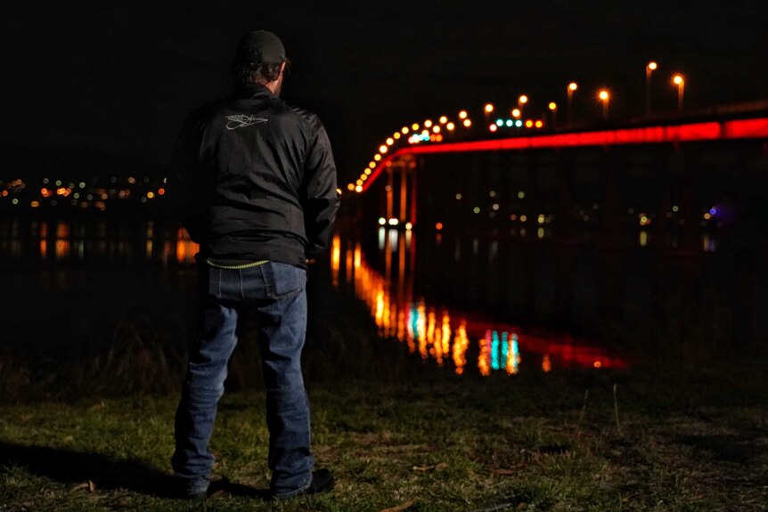 Homeless man looks at bridge.