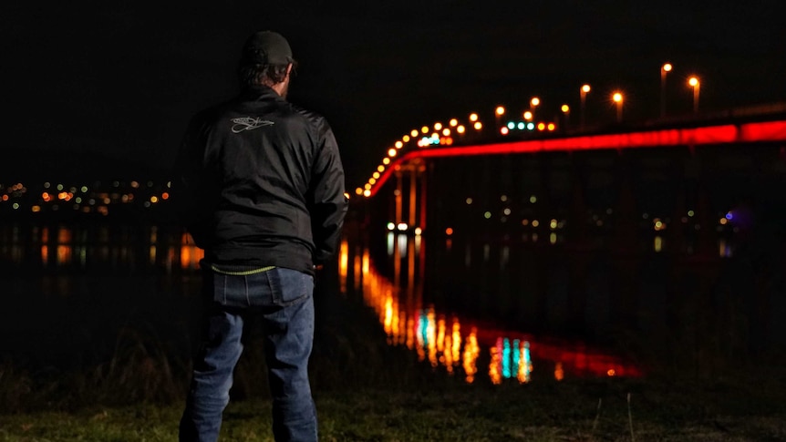 Homeless man looks at bridge.