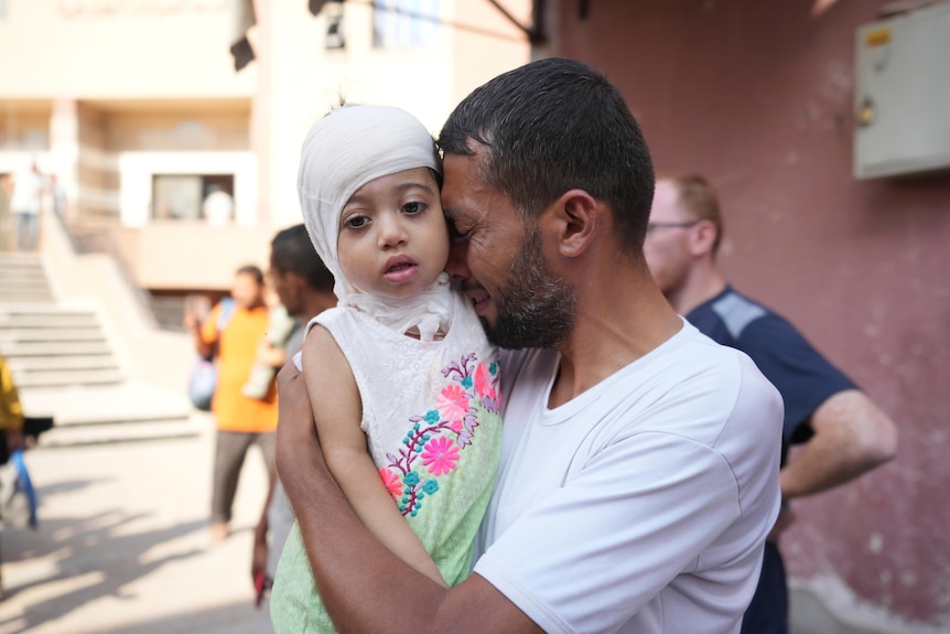 A Palestinian man reacts as he says goodbye to his sick daughter 