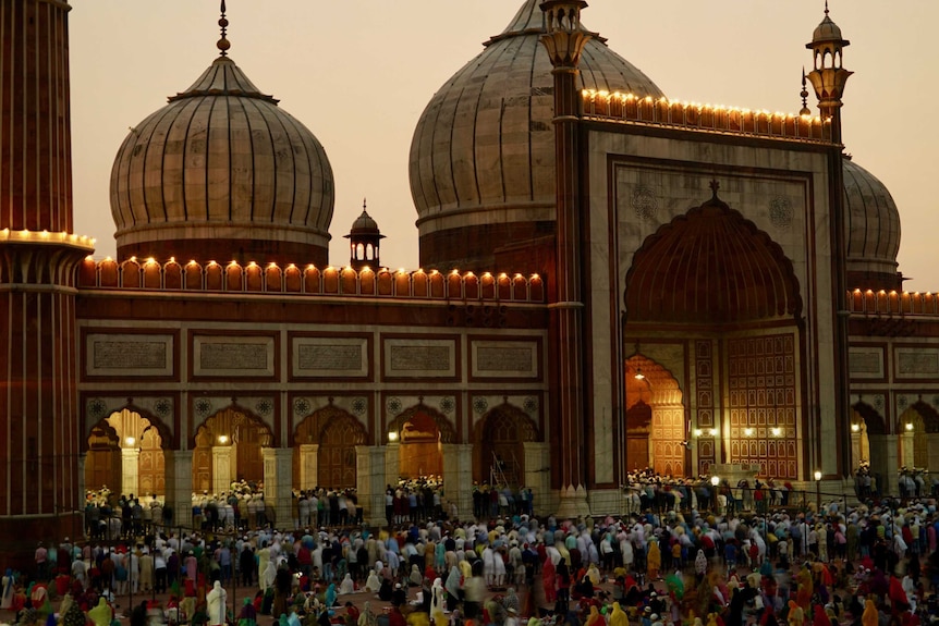 A crowd gathers outside a mosque to pray in the early evening.