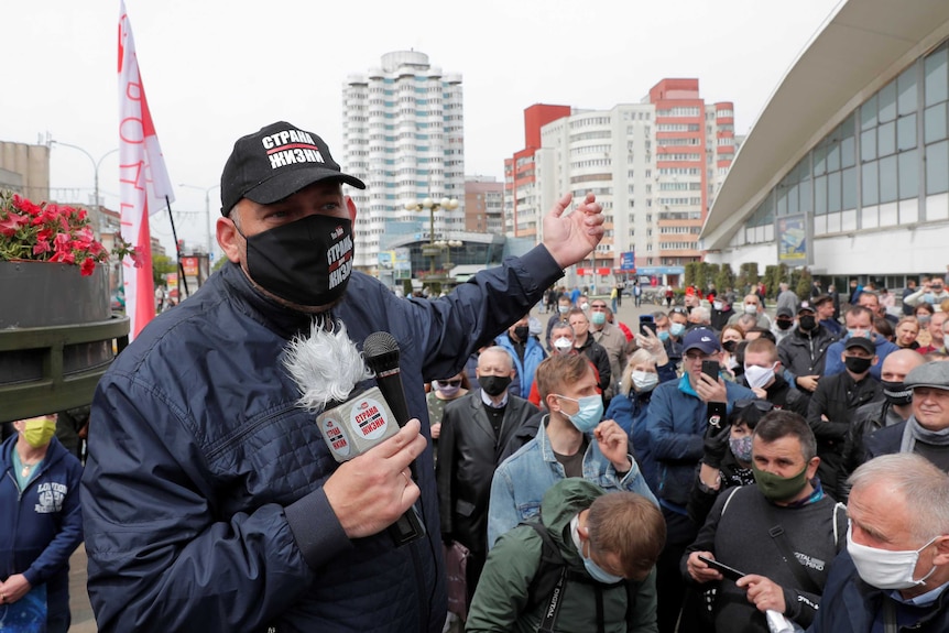 Sergei Tikhanovsky wears a cap and speaks during a rally of supporters of opposition politicians.