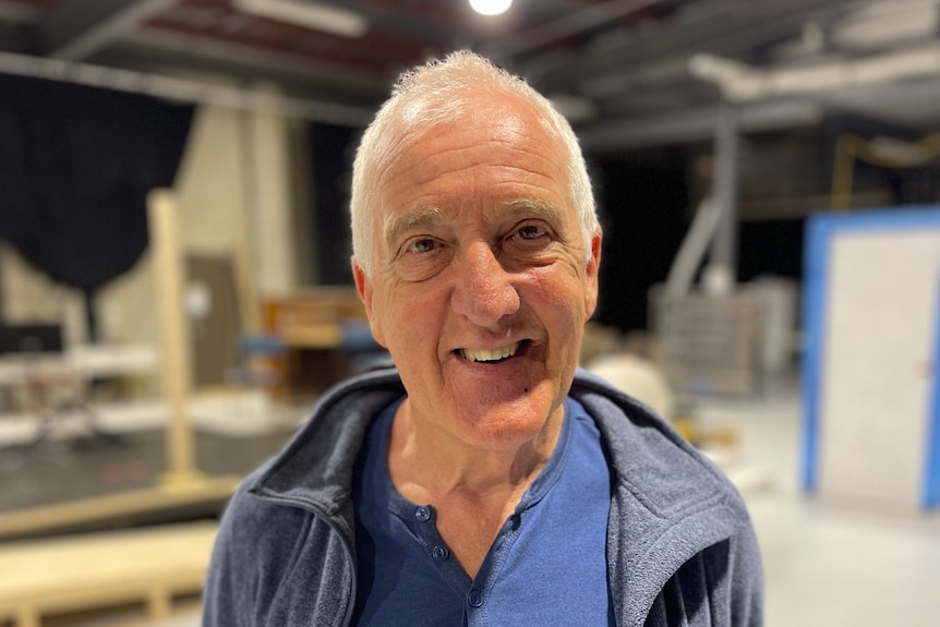 A close up of a smiling man with white hair