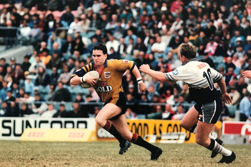 A player takes on a defender in a rugby league match