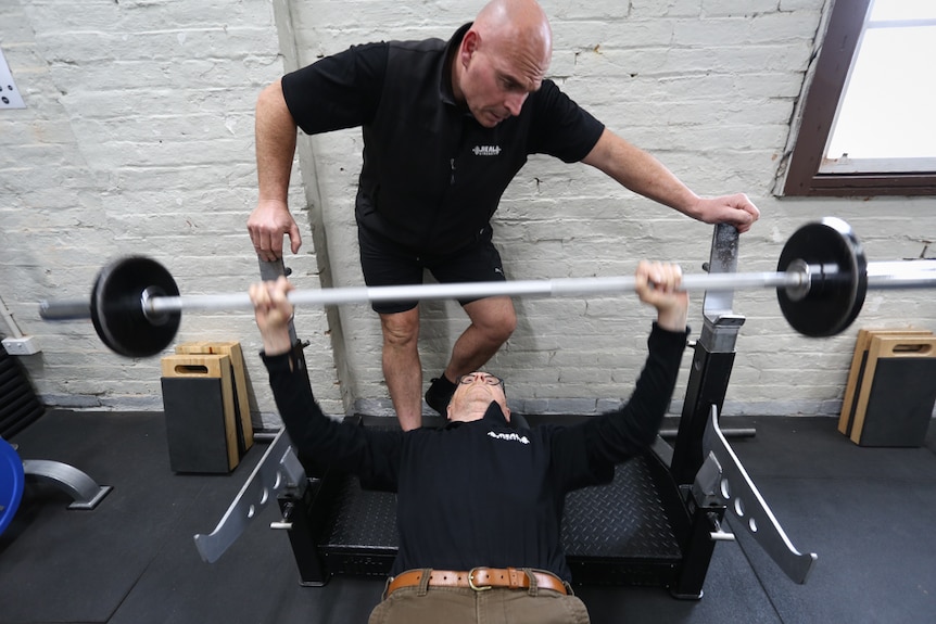 Tony bench pressing with head coach Dean Mawby overseeing his routine.