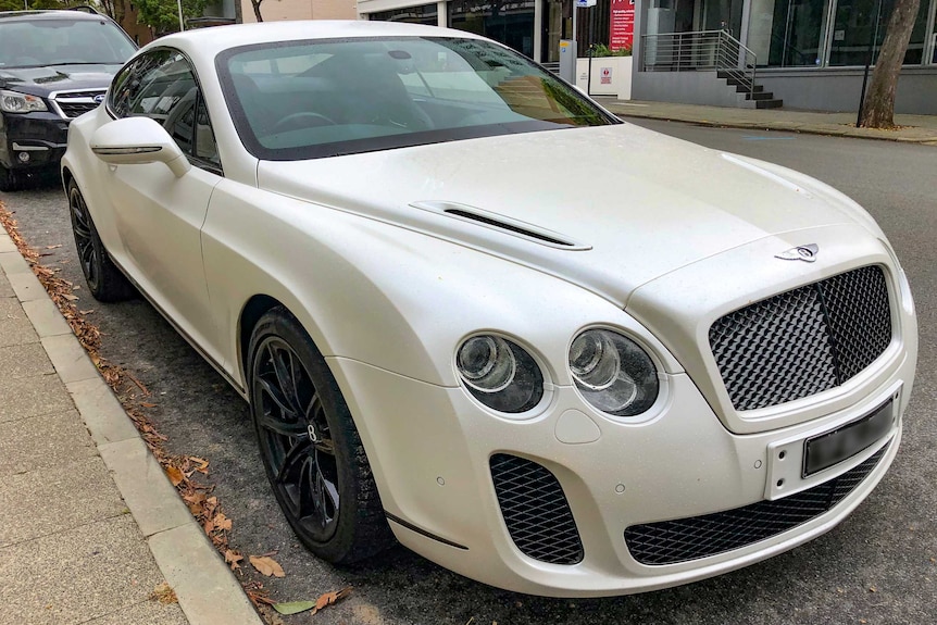 A white Bentley parked on the side of the road.