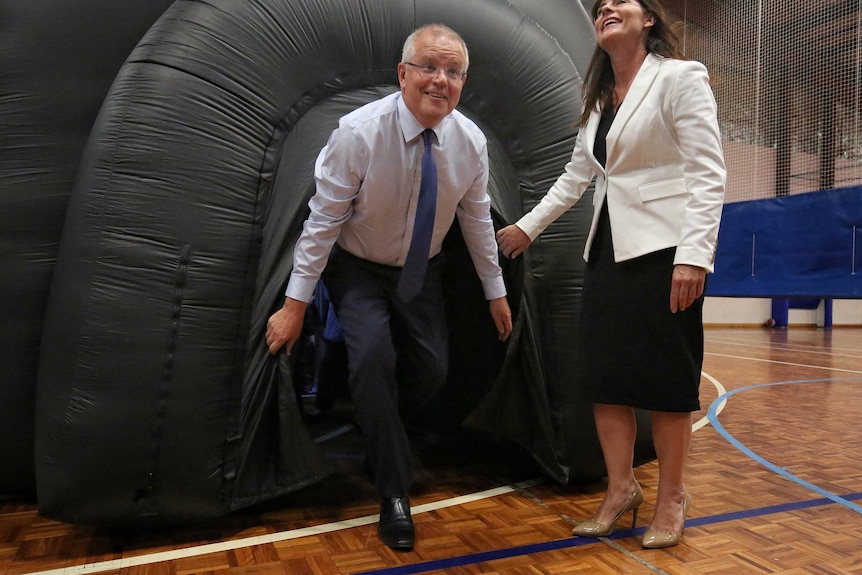 Scott Morrison emerges from a black inflatable balloon inside a gymnasium