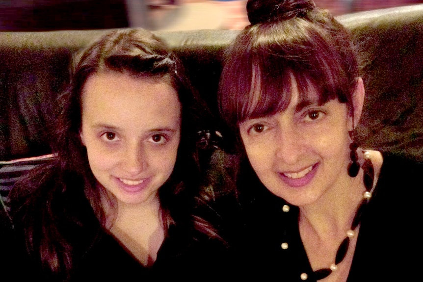 A daughter and her mother smile at the camera.
