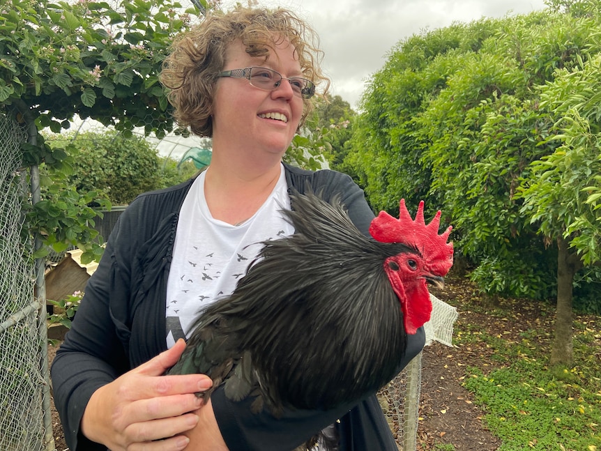 A woman holds a chicken.
