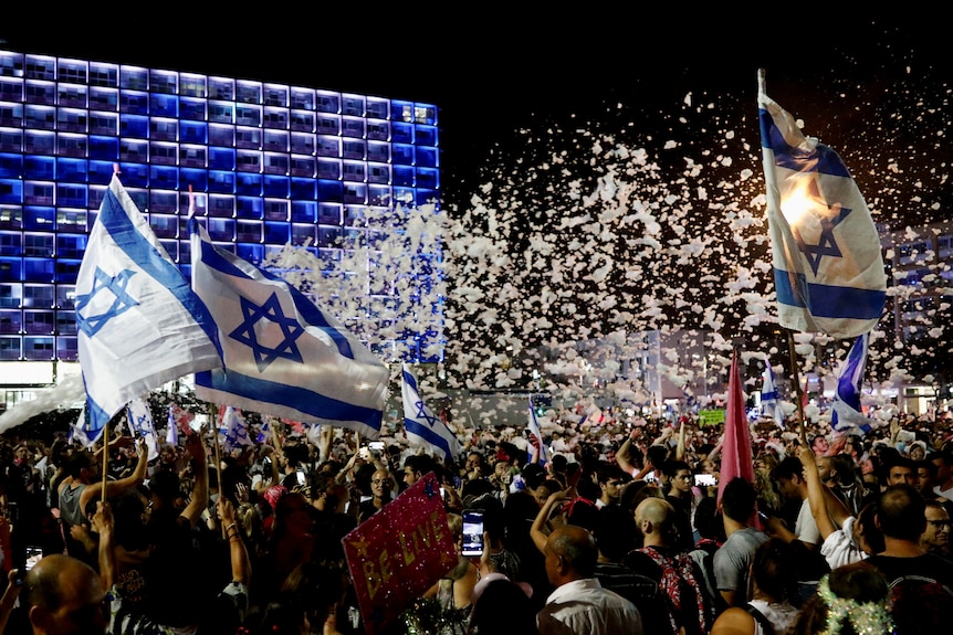 Israelis wave national flags and get sprayed with foam in Tel Aviv as they celebrate the new government
