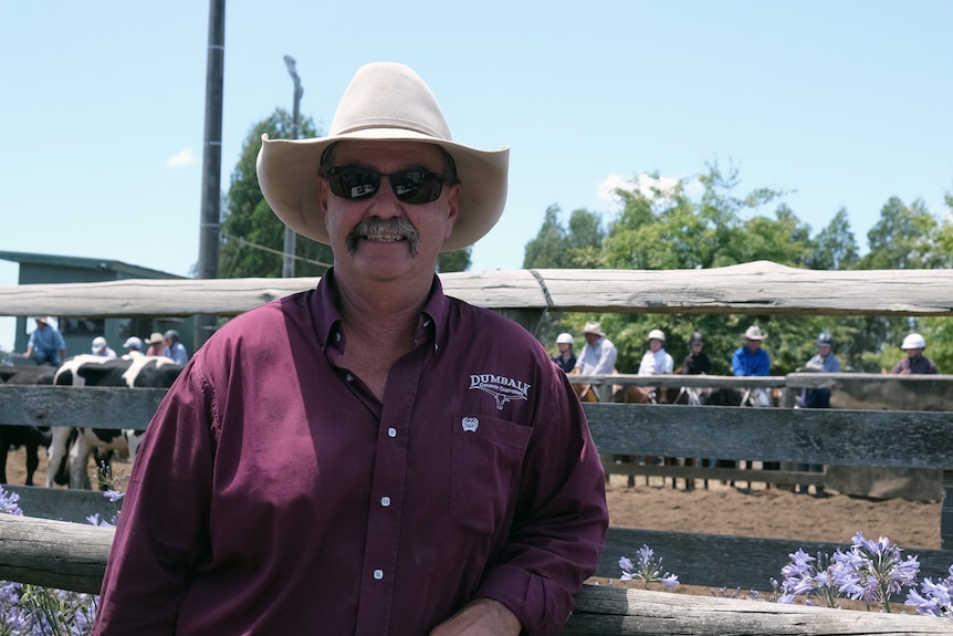 Ian stands in front of the camp wearing sunglasses, a pale Akubra and a purple shirt