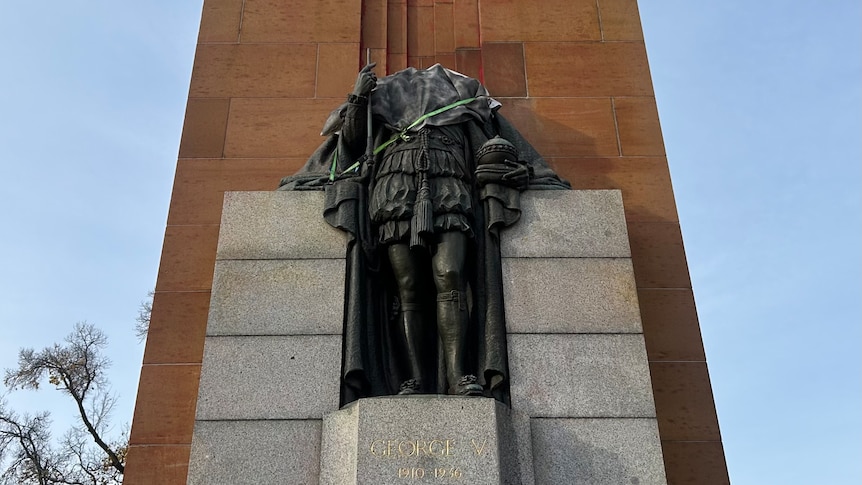 A statue of King George without his head and red paint splattered behind it. 