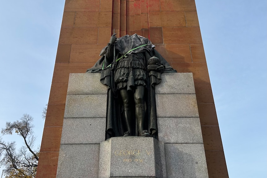 A statue of King George without his head and red paint splattered behind it. 