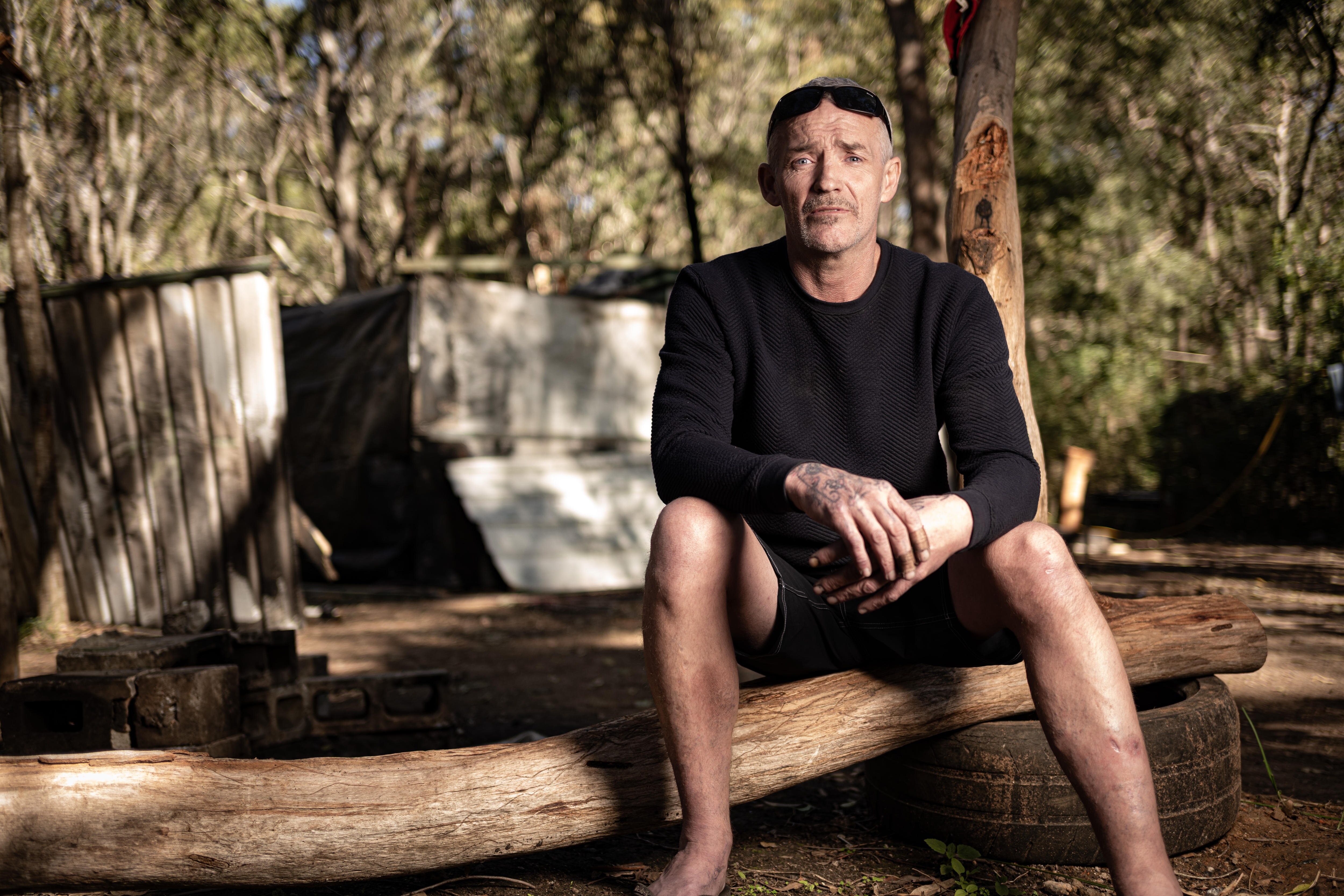 A man sits next to an iron fence