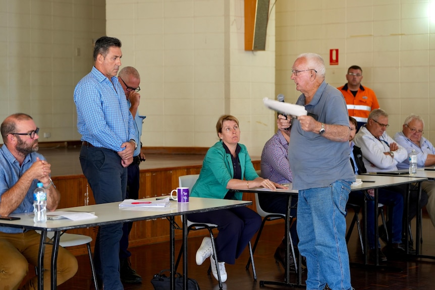 A man standing talking and people listening 