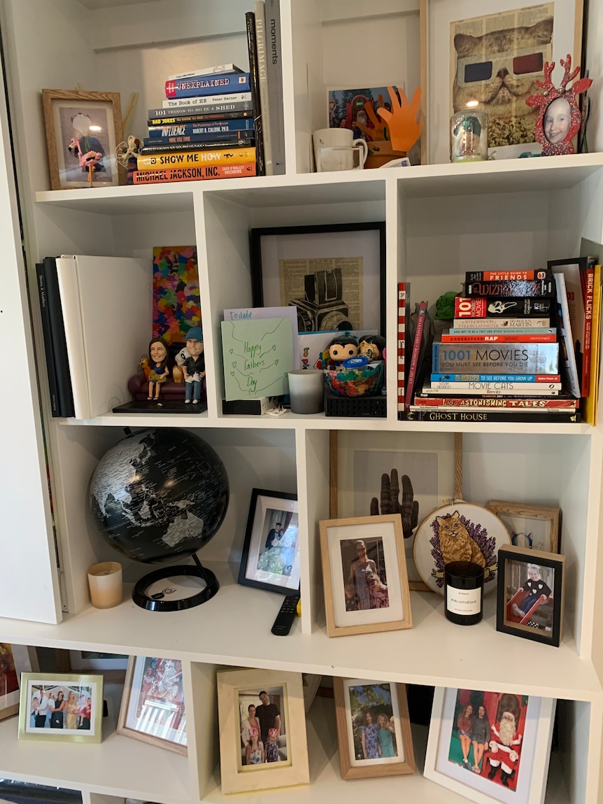 A series of white shelves, filled with family photos, books and ornaments