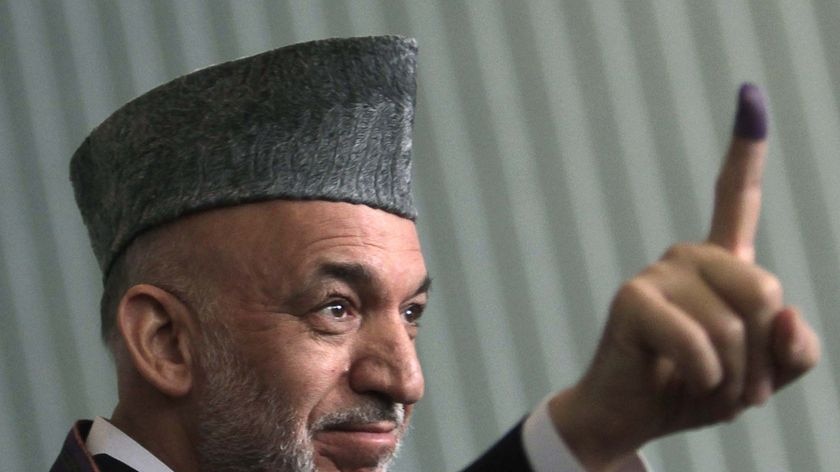 Afghan President Hamid Karzai holds up his inked stained finger after voting