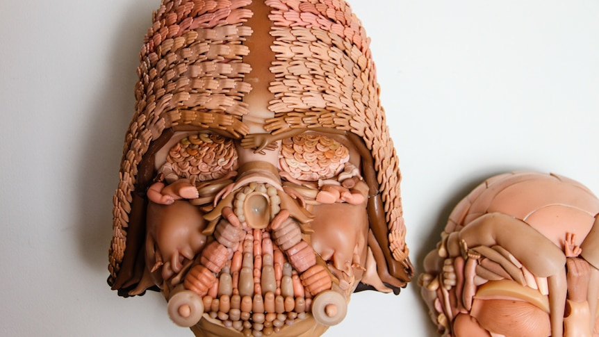 A mask made from tiny pieces of toy dolls
