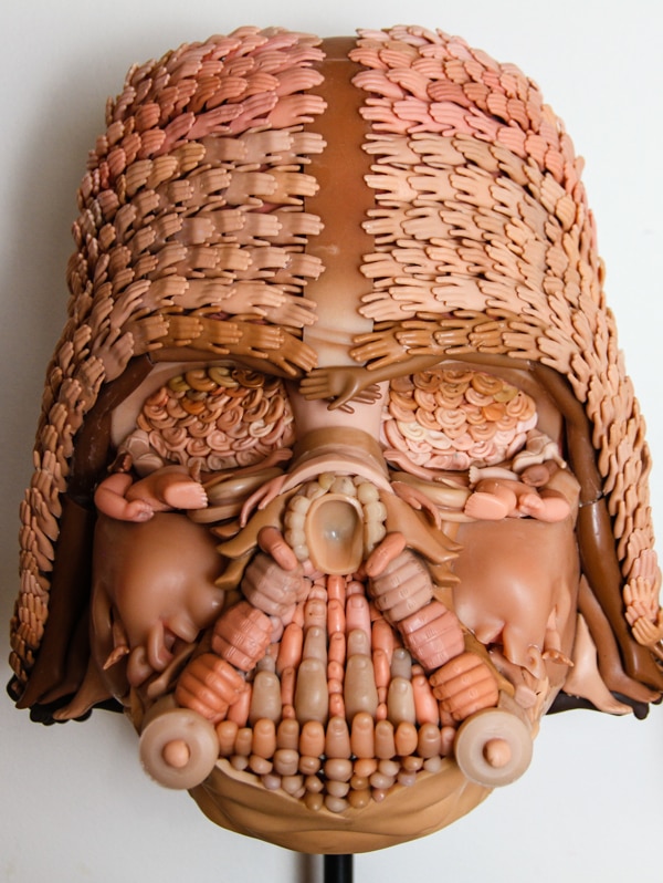 A mask made from tiny pieces of toy dolls