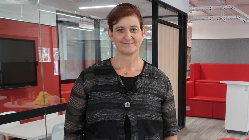 Stephanie McConnell stands next to a meeting room