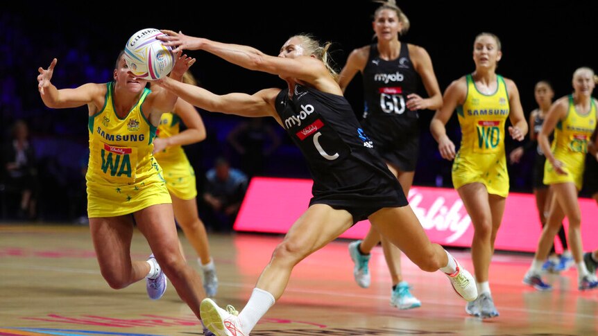 Netballers lunge for the ball during a contest