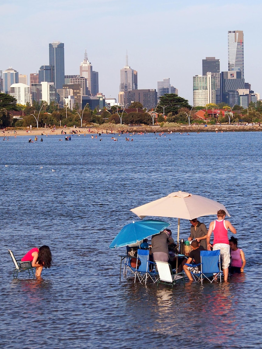A family having a picnic cools off at Port Melbourne beach.