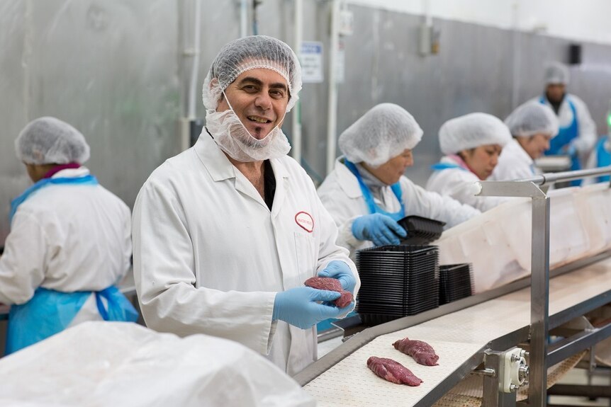 The founder and director of Macro Meats, Ray Borda, is holding a piece of kangaroo steak on his hand, standing in his factory.