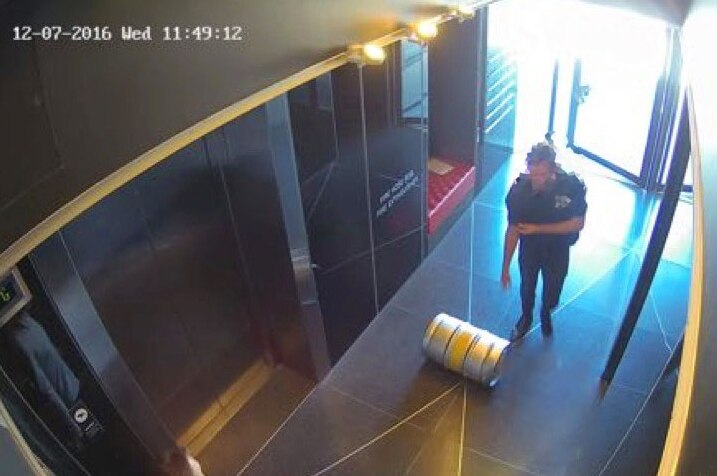 A beer keg being rolled across the floor of an apartment foyer.