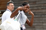 A young woman gestures at the camera while carrying a sports bag