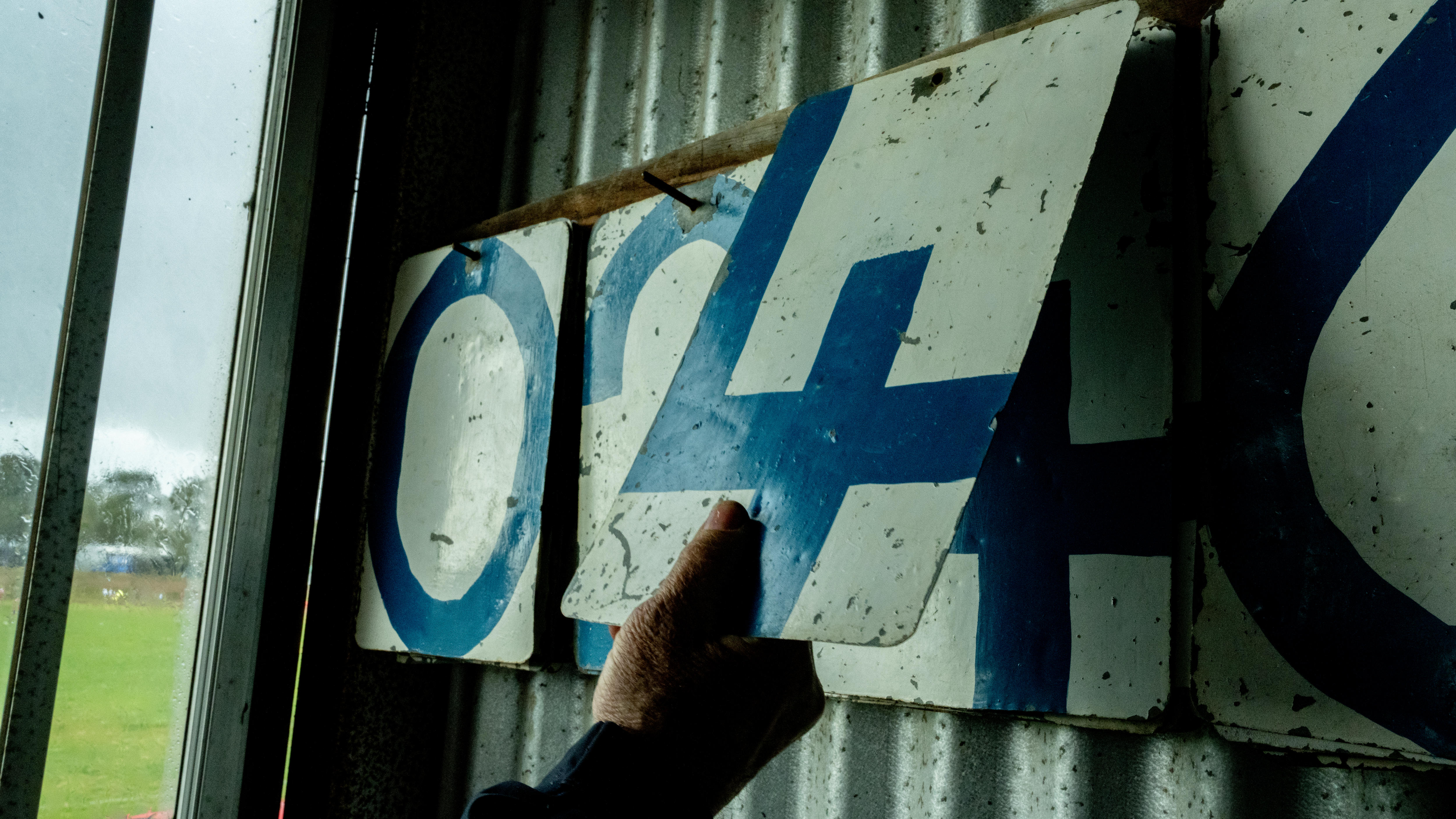 A hand turning a old fashioned scoreboard.