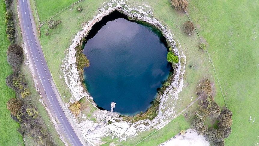 An aerial shot of a sinkhole filled with water.