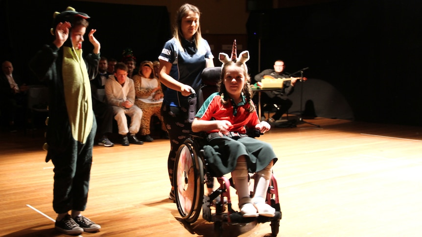 A group of people, mostly children, on the stage floor during rehearsals