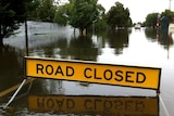 A road sign sits in the middle of floodwaters covering Fowler Street in Tallygaroopna.