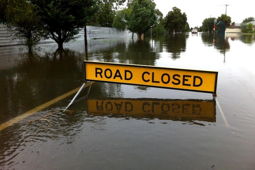 A road sign sits in the middle of floodwaters covering Fowler Street in Tallygaroopna.