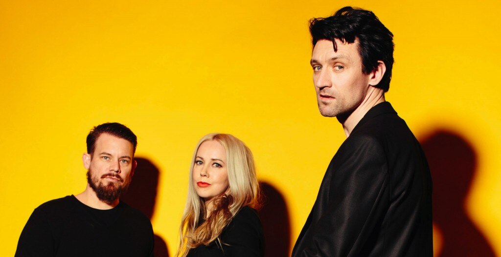 Clint Hyndman, Stephanie Ashworth and Paul Dempsey of Something For Kate stand in front of a golden backdrop