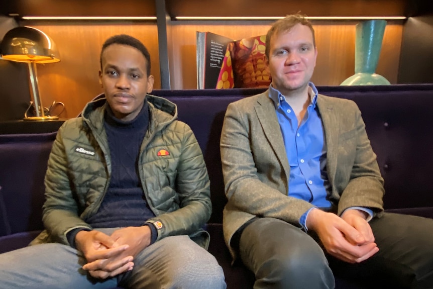 Ali Ahmad and Matthew Hedges sitting on a couch. 