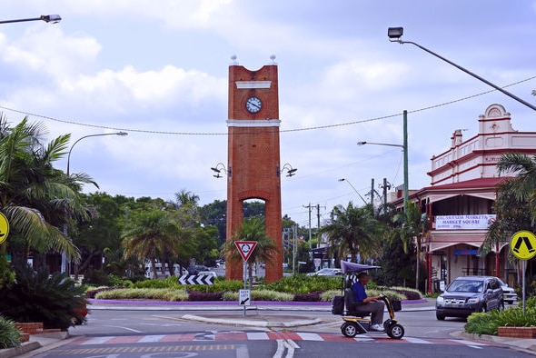 A historic looking clock tower in the middle of a country town.