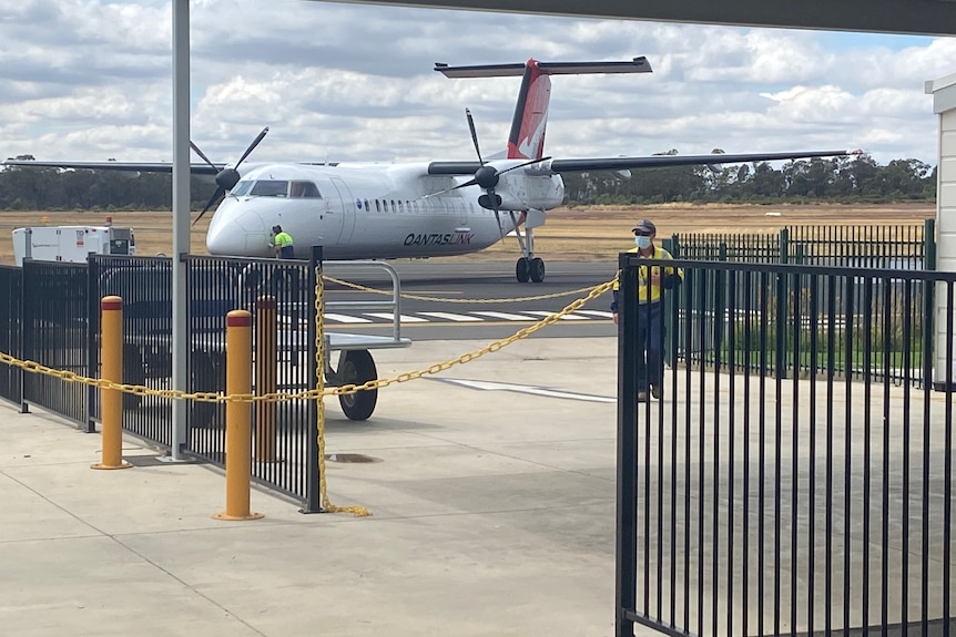 outdoor baggage area at an airport with a Qantas Airplane behind.