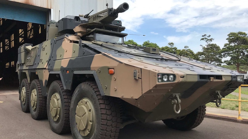 A military vehicle at an industrial site.