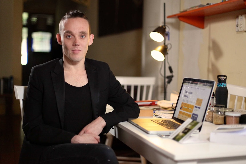 Jesse Lewis is pictured sitting at a desk in front of a computer.