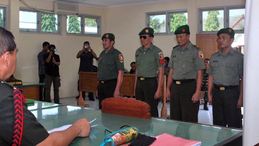 Four Indonesian soldiers stand at attention at their trial at the Madiun district military court.