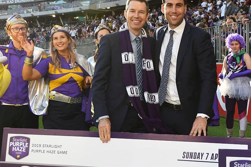 Selby Lee-Steere is pictured in a suit at a Fremantle home game, donating money to the Starlight Foundation
