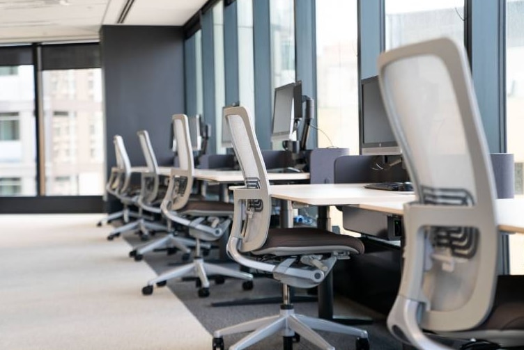 A row of empty office chairs facing a window.