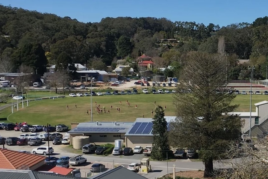 A country oval with trees and hills